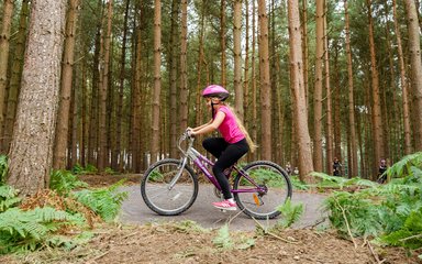 Girl cycling through a forest