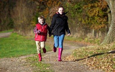 Children running on muddy forest path in wellies