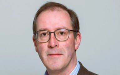 Head shot of a white man with short hair wearing glasses.