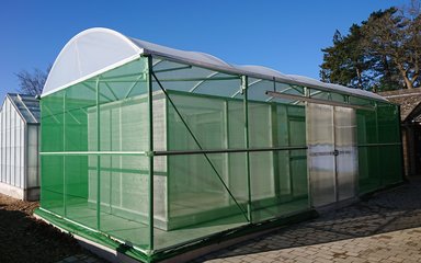 A long domed structure covered with green mesh with a visible inner rectangle section