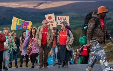 Harold Fry and a group walking through the countryside with cardboard signs