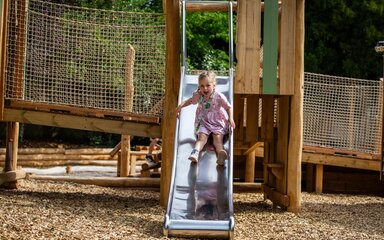 girl on slide in wooden play area 
