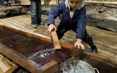 children playing with water feature play area in a forest