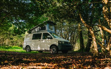 A white camper van surrounded by trees