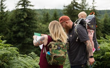 Family with baby looking at map in forest