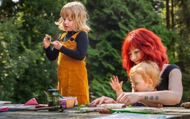 Family sit at a picnic bench in the forest