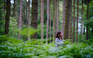 Woman stood amongst large leaves in the forest