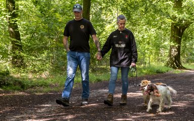 Two walkers in jeans and black tops walking with two spaniels