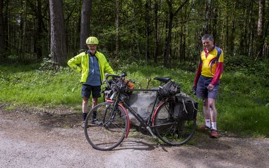 Two male cyclists taking a break with their bikes leaning against a large rock