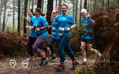 waving woman in group of runners in a forest