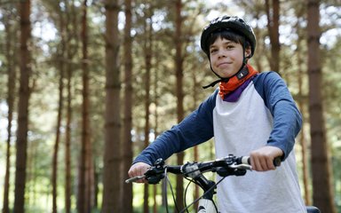 Boy in cycling helmet on a bike in a forest