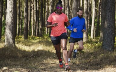 A woman and man running through the forest