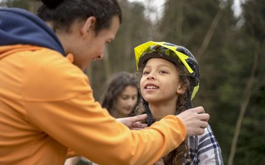 Dad helping child put cycling helmet on