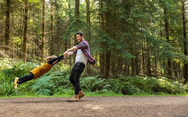 Child being spun around playing in the forest