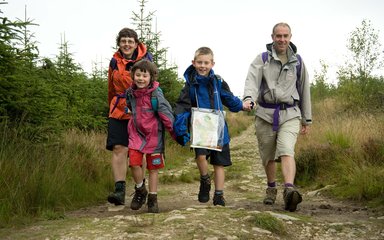 Family of four walking through the forest on a rocky path