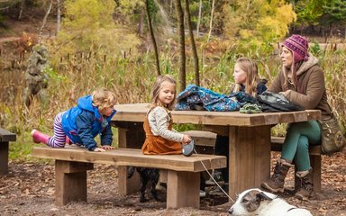 Family with dog on lead picnicking 