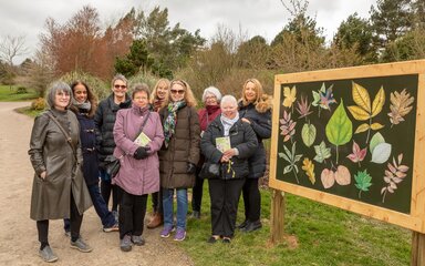A group of artists standing next to an exhibition board 