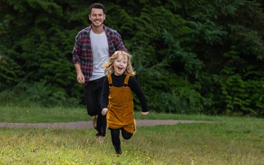 Child happily play running through grass 