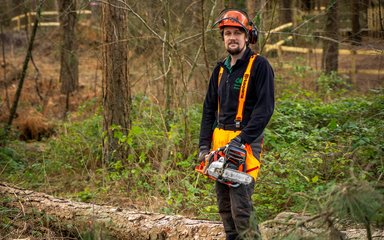 Staff wearing PPE and holding a chainsaw