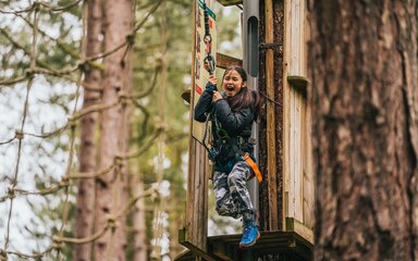 Older child on Go Ape activity high up in a forest
