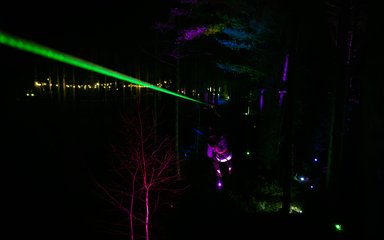 A person swinging through trees at Go Ape in the dark 