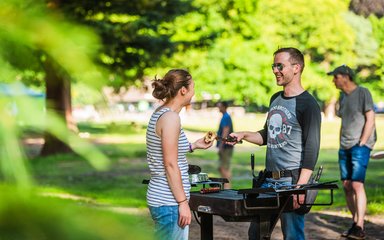 Man hands woman sausage at BBQ