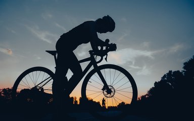 Silhouette of woman cycling at sunset
