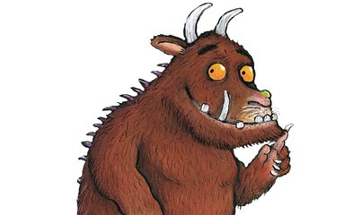 A cartoon image of the Gruffalo - a fictional creature with 2 spikes coming out of his head, wide orange eyes, brown fur, a green wart on his nose, a big long tooth, and purple spikes running down his back