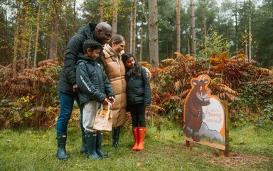 Family in an Autumn forest looking at Gruffalo panel