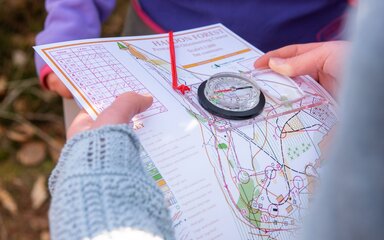 Close-up of hands holding a map and compass.