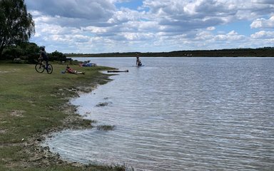Hatchet pond in the sunshine with a cyclist and paddleboarder nearby