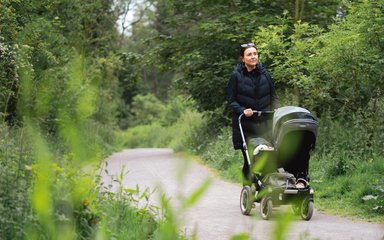 A woman pushing a pram along a trail in a forest