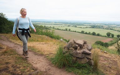 A women walking along a trail on a hillside, looking at the view