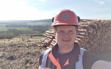 Forester taking selfie in front of a timber stack