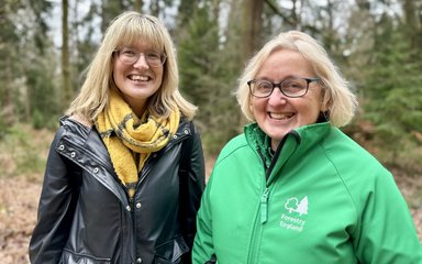 Two women smiling in a forest