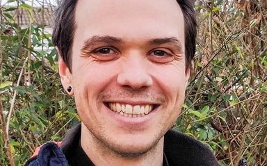 A man with dark spikey hair smiles at the camera