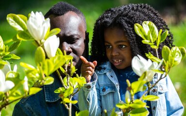 A young boy and his Dad take a closer look at a white flower