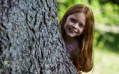 Child behind tree