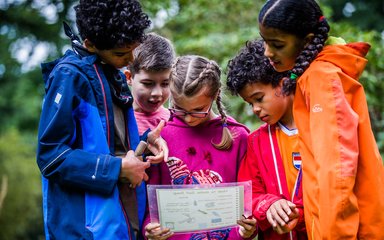 A group of children looking at a piece of paper in the forest
