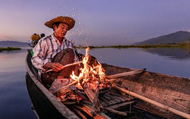 Earth Photo shortlisted work - photo of man creating a fire on a boat on a lake