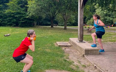 Two people training outside in a forest park setting.
