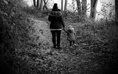 Black and white photo of mother and child walking along trail (backs to camera)