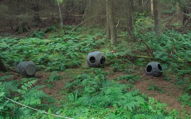 3 hollowed round sculptures in the forest floor