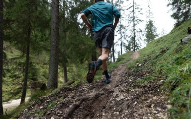 Man running on a small, hilly trail in the forest