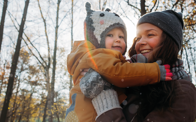 smiling woman holding toddler with winter hats