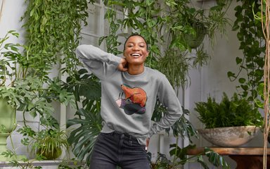 Women in a grey top smiling in a conservatory filled with plants