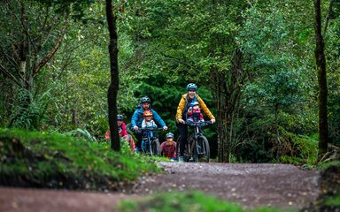 Family cycling on a trail surrounded by woodland 