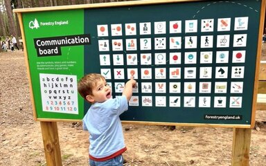 A child pointing to a symbol on a large board covering in symbols.