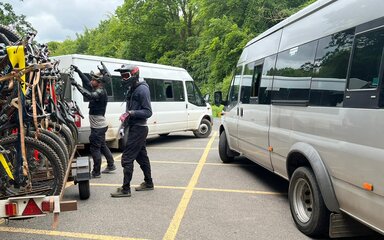 Two mountain bikers loading their bikes onto the trailer of an uplift service.