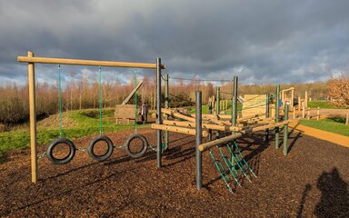 Timber play equipment featuring climbing net and hanging tyres
